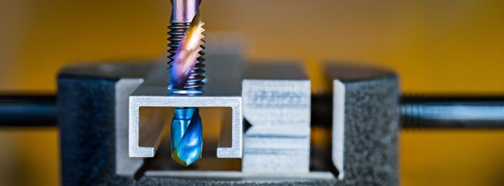 Steel tap and drill bit with blue purple nano titanium coating on a brown background